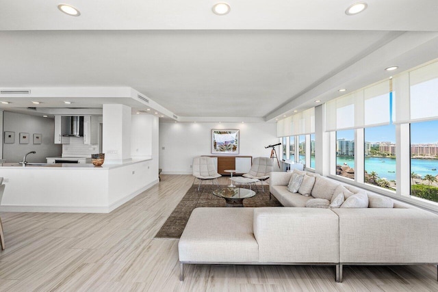 living area featuring plenty of natural light, recessed lighting, light wood-style flooring, and a water view