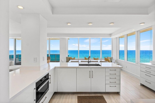 kitchen with a sink, stainless steel oven, a water view, modern cabinets, and recessed lighting
