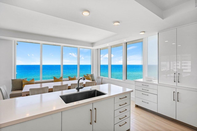 kitchen featuring a sink, a water view, light countertops, and recessed lighting