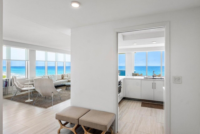 corridor featuring a water view, a sink, healthy amount of natural light, and recessed lighting