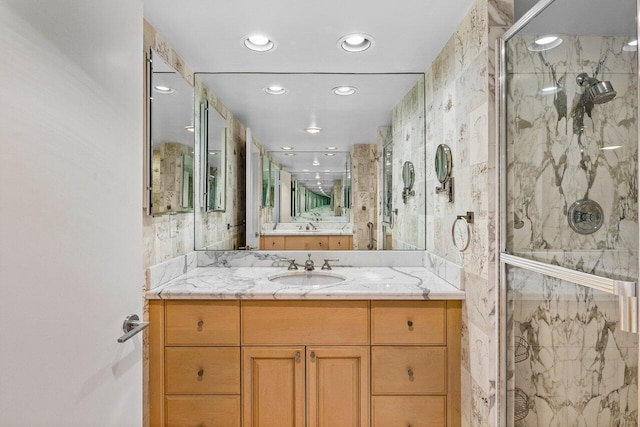 bathroom with a marble finish shower, vanity, and recessed lighting