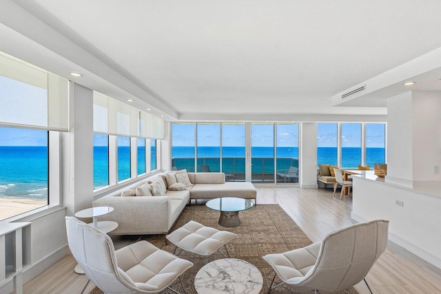 living area with a water view, light wood-style flooring, baseboards, and recessed lighting