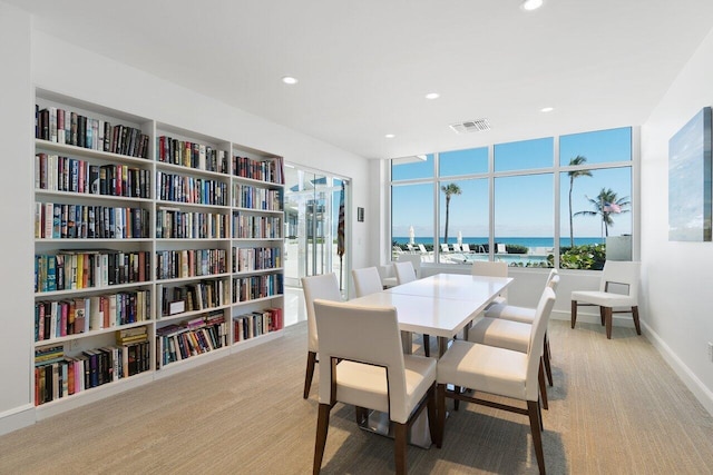 dining space with light colored carpet, healthy amount of natural light, recessed lighting, and a water view