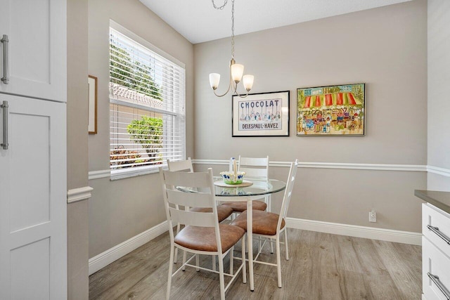 dining space featuring light wood-style flooring, baseboards, and a chandelier