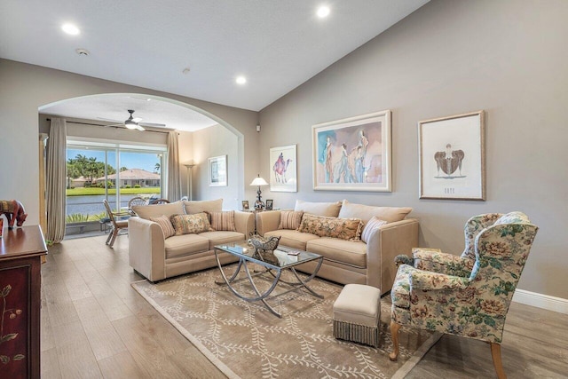 living room with arched walkways, wood finished floors, ceiling fan, vaulted ceiling, and recessed lighting