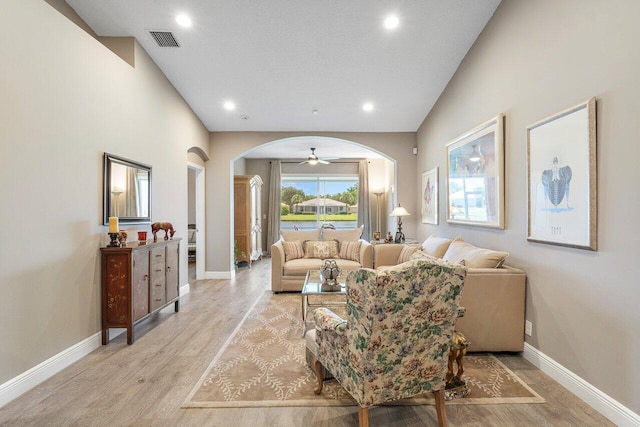 living room with arched walkways, light wood-type flooring, baseboards, recessed lighting, and ceiling fan