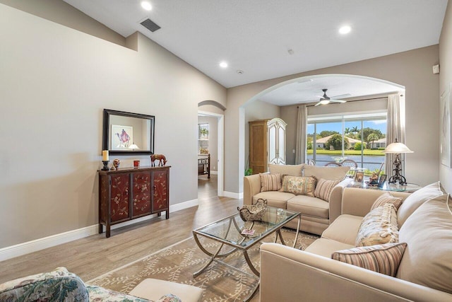 living room with arched walkways, ceiling fan, plenty of natural light, vaulted ceiling, and light wood finished floors