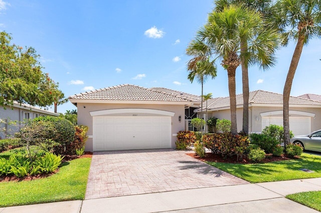 view of front of home featuring stucco siding, a garage, a tiled roof, and decorative driveway