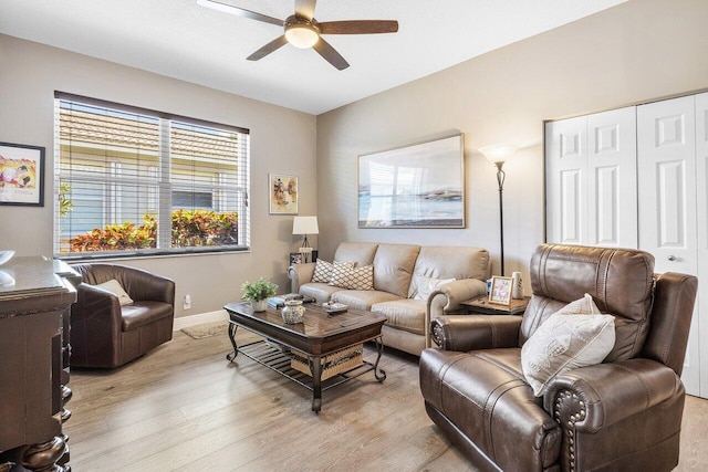 living room with a ceiling fan, light wood-style floors, and baseboards