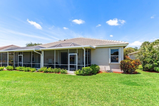 back of property with a sunroom, a tile roof, a yard, and stucco siding