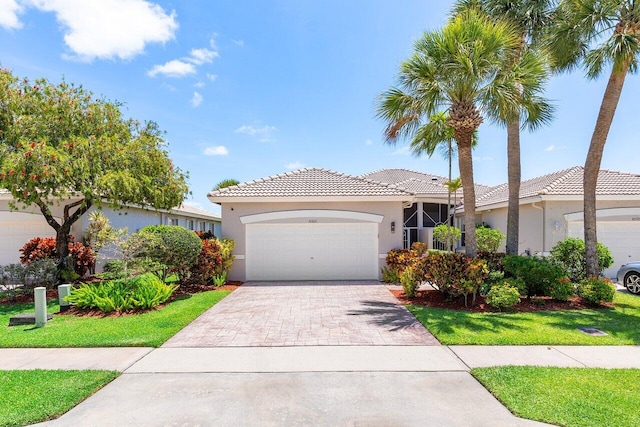 view of front of home with stucco siding, a tile roof, a garage, and driveway