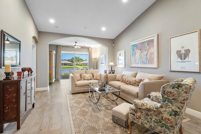 living area with arched walkways, light wood-style flooring, baseboards, recessed lighting, and vaulted ceiling