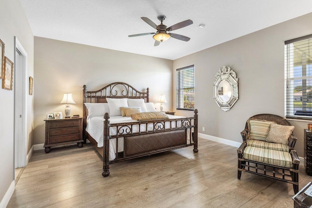 bedroom featuring light wood finished floors, baseboards, and a ceiling fan