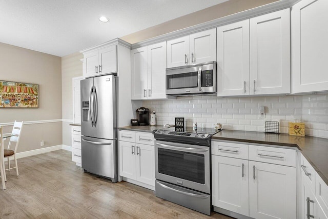 kitchen featuring stainless steel appliances, dark countertops, tasteful backsplash, recessed lighting, and light wood-type flooring