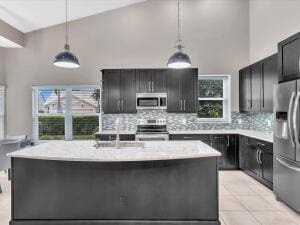 kitchen with appliances with stainless steel finishes, a sink, plenty of natural light, decorative backsplash, and a high ceiling