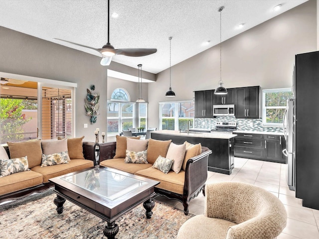living room featuring a textured ceiling, high vaulted ceiling, ceiling fan, and light tile patterned floors