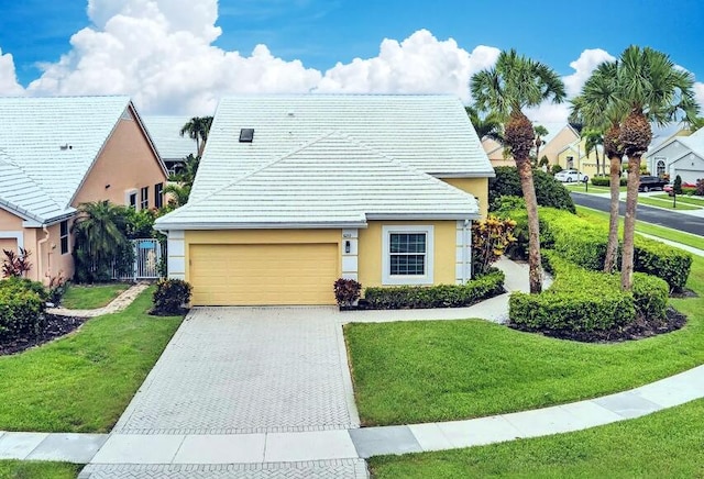 view of front facade featuring an attached garage, a front lawn, driveway, and stucco siding