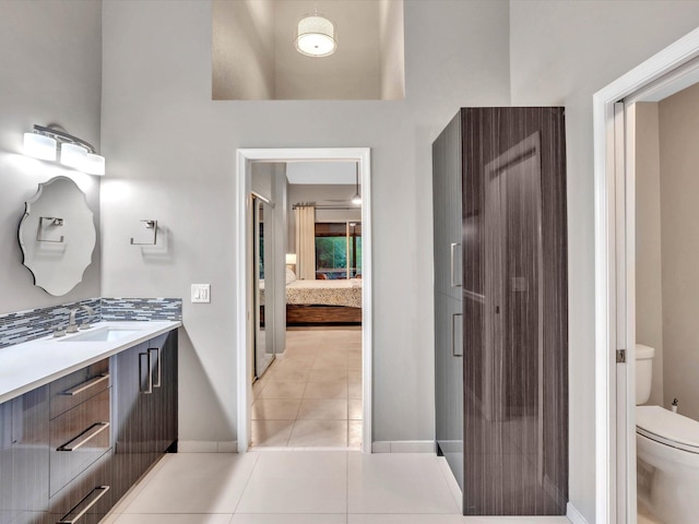 bathroom featuring ensuite bath, toilet, tile patterned flooring, baseboards, and vanity