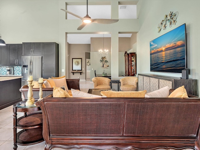 living area with a towering ceiling, light tile patterned floors, a ceiling fan, and a chandelier