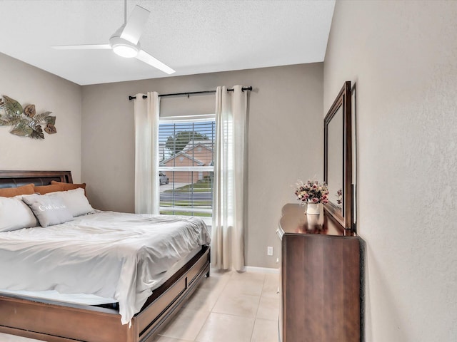 bedroom featuring light tile patterned floors, a ceiling fan, baseboards, and a textured ceiling