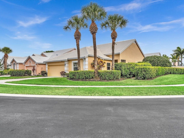 view of front of house featuring a garage, a tiled roof, stucco siding, a front lawn, and driveway