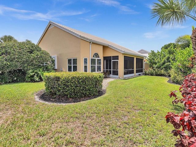 back of house featuring a lawn, stucco siding, and a sunroom