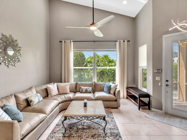 living area featuring high vaulted ceiling, healthy amount of natural light, light tile patterned floors, ceiling fan, and baseboards