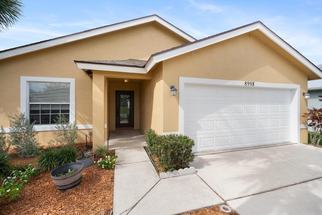 8998 SW Bonneville Dr, Stuart, FL 34997 - view of front of property with stucco siding, a garage, and driveway