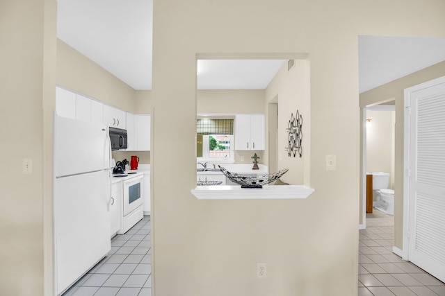 kitchen with white appliances, white cabinetry, light tile patterned floors, and light countertops