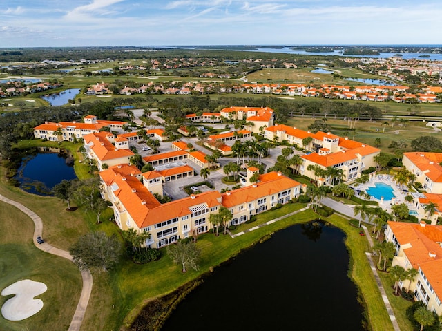 bird's eye view of a nearby body of water, apartment complex, and a golf course