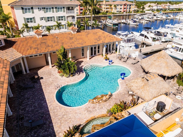 community pool with view of marina, a patio, and a water view