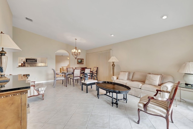 living area with vaulted ceiling, light tile patterned floors, a chandelier, baseboards, and arched walkways