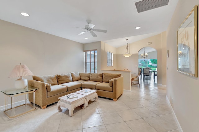living area featuring ceiling fan, baseboards, arched walkways, a chandelier, and light tile patterned floors