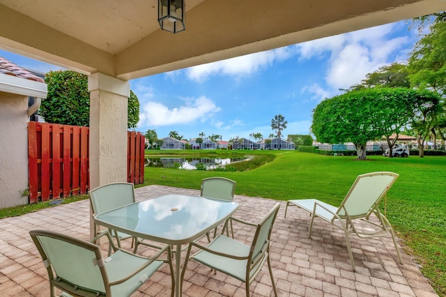 view of patio featuring a water view, outdoor dining space, and a residential view