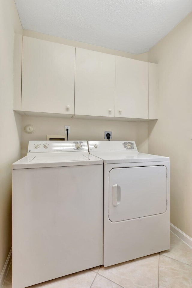 washroom with washer and dryer, cabinet space, baseboards, and light tile patterned flooring