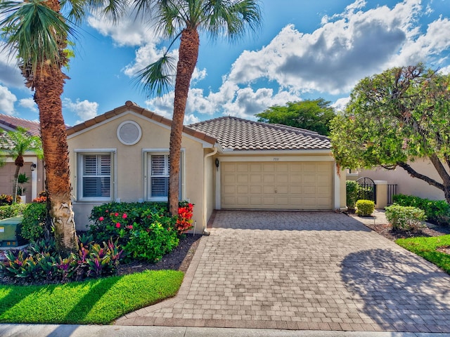 mediterranean / spanish house with stucco siding, a garage, decorative driveway, and a tile roof