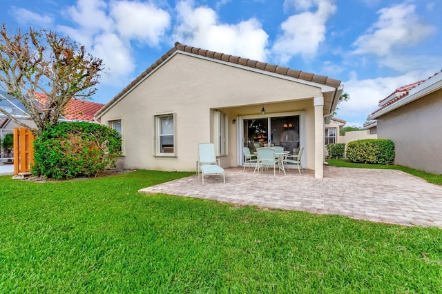 back of house with a patio, a lawn, stucco siding, and a tile roof