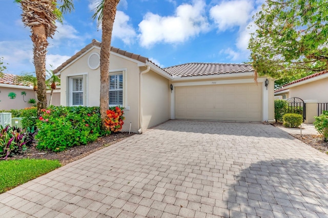 view of front facade featuring stucco siding, a garage, decorative driveway, and a tiled roof