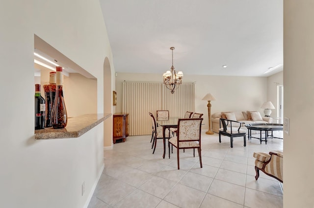 dining room featuring a chandelier, light tile patterned flooring, arched walkways, and baseboards