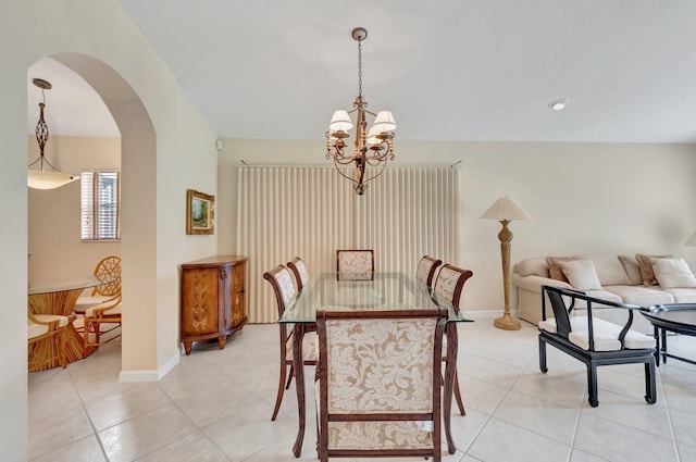 dining space featuring a chandelier, arched walkways, light tile patterned flooring, and baseboards