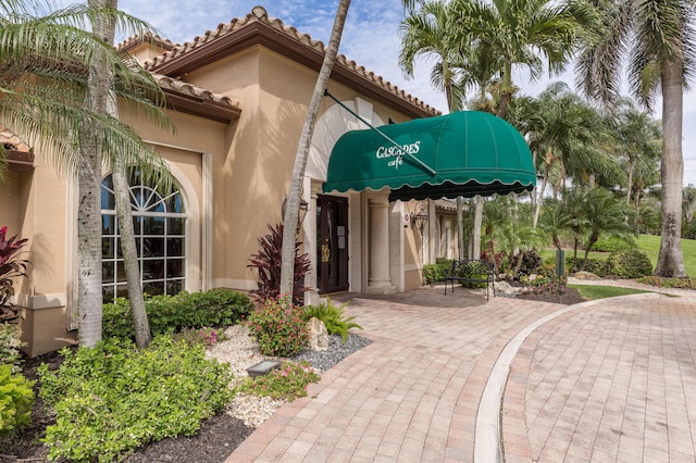 view of exterior entry featuring stucco siding and a tiled roof