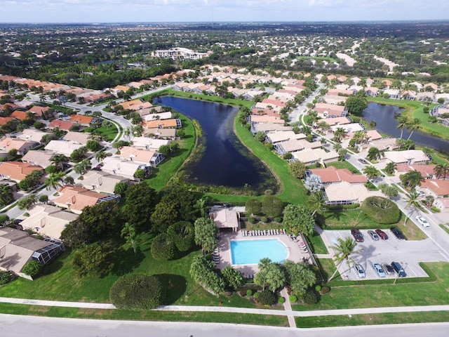 aerial view of property and surrounding area featuring a nearby body of water, a pool area, and nearby suburban area
