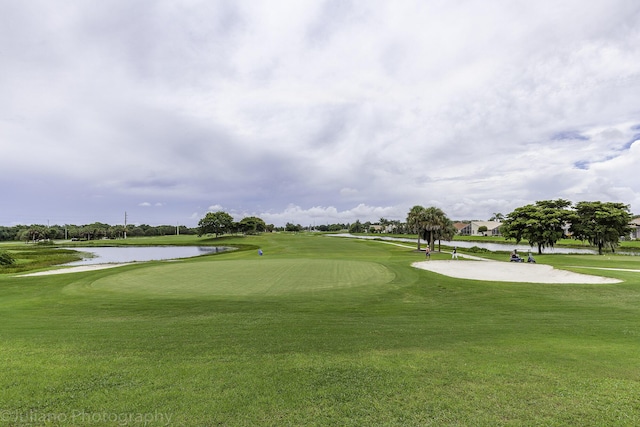 view of community with a water view, golf course view, and a lawn