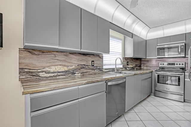 13446 Sabal Palm Ct Unit A, Delray Beach, FL 33484 - kitchen featuring stainless steel appliances, gray cabinets, a sink, decorative backsplash, and a textured ceiling
