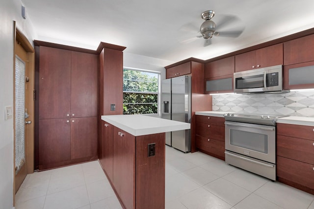 kitchen featuring stainless steel appliances, a peninsula, light countertops, ceiling fan, and tasteful backsplash