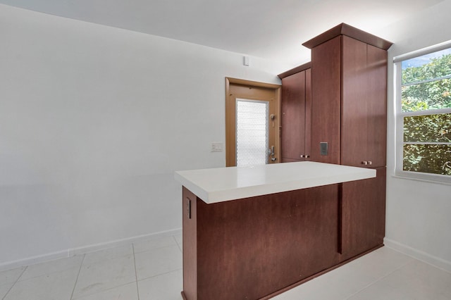 kitchen featuring baseboards, light countertops, a peninsula, and light tile patterned floors