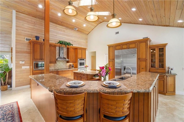 kitchen featuring built in appliances, wood ceiling, a large island, wall chimney range hood, and high vaulted ceiling