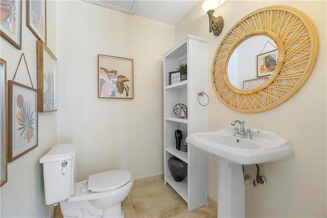 half bathroom with toilet, baseboards, and tile patterned floors