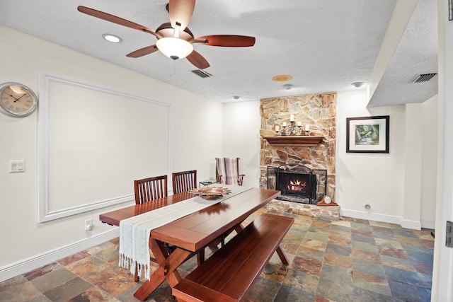 2414 SW Love Ct, Palm City, FL 34990 - dining area featuring baseboards, stone tile floors, a ceiling fan, a stone fireplace, and a textured ceiling