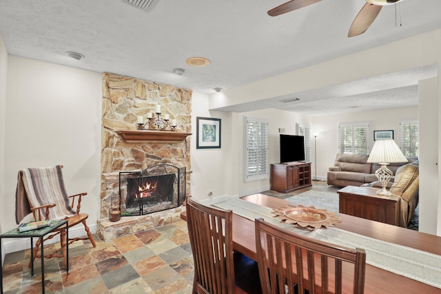 2414 SW Love Ct, Palm City, FL 34990 - dining area with ceiling fan, baseboards, a fireplace, a textured ceiling, and stone finish flooring